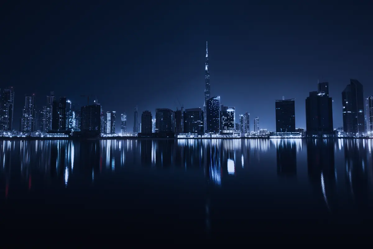 The Dubai skyline at night reflected in still water.
